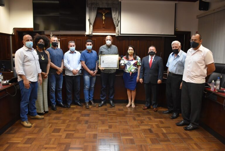 Representantes da UNEI participam de uma cerimônia oficial de reconhecimento institucional. O grupo posa para uma foto ao lado de autoridades, com um certificado em destaque no centro da imagem, simbolizando o reconhecimento do trabalho desenvolvido pela organização em prol da promoção da igualdade racial e da cultura negra.